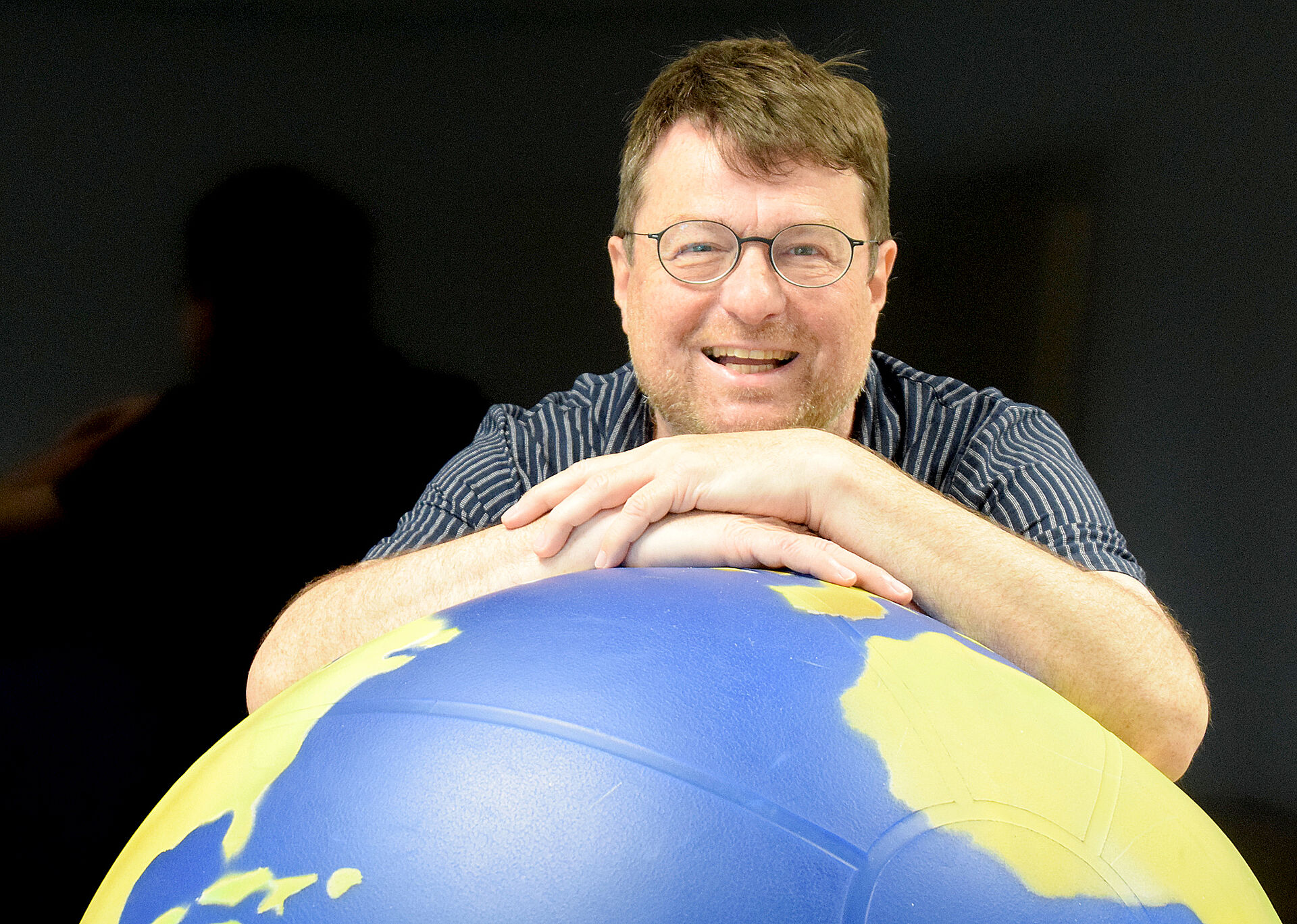 Markus Heißler lehnt sich auf eine Weltkugel