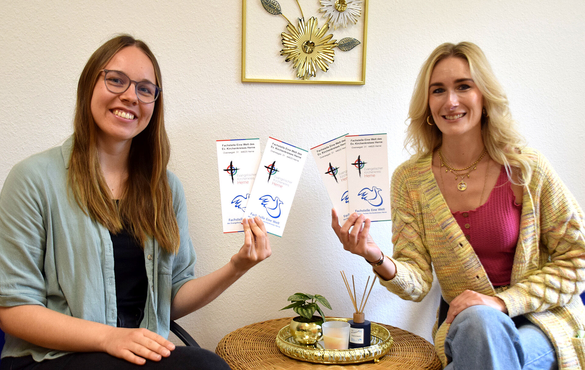 Nina Bauer und Anna Hopfe halten Flyer der Fachstelle eine Welt in der Hand